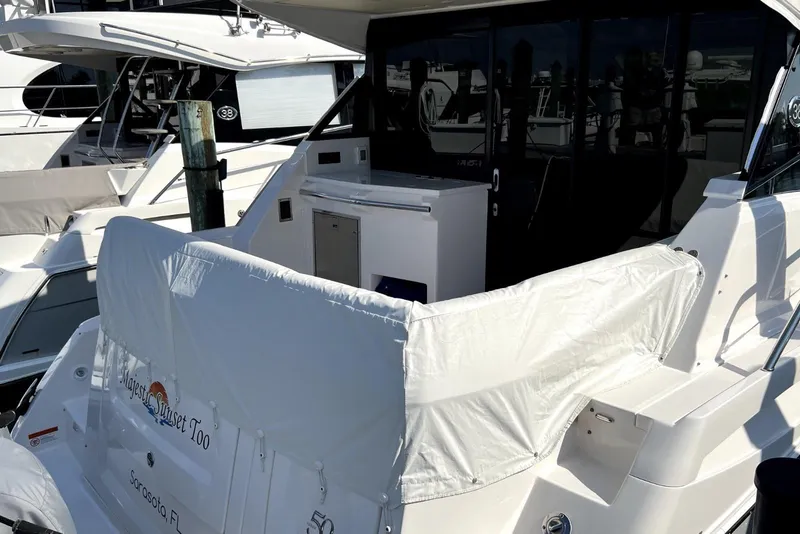 Slide: The Image of 2021 Regal 38 XO yacht docked, featuring covered seating and sleek design. - 2