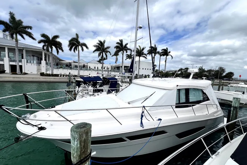Slide: The Image of 2021 Regal 38 XO yacht docked at marina with palm trees and cloudy sky. - 3