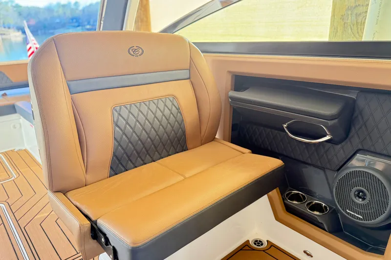 Slide: The Image of 2025 Cobalt R33 boat interior with luxurious tan and black seating, speaker, and cup holders. - 21