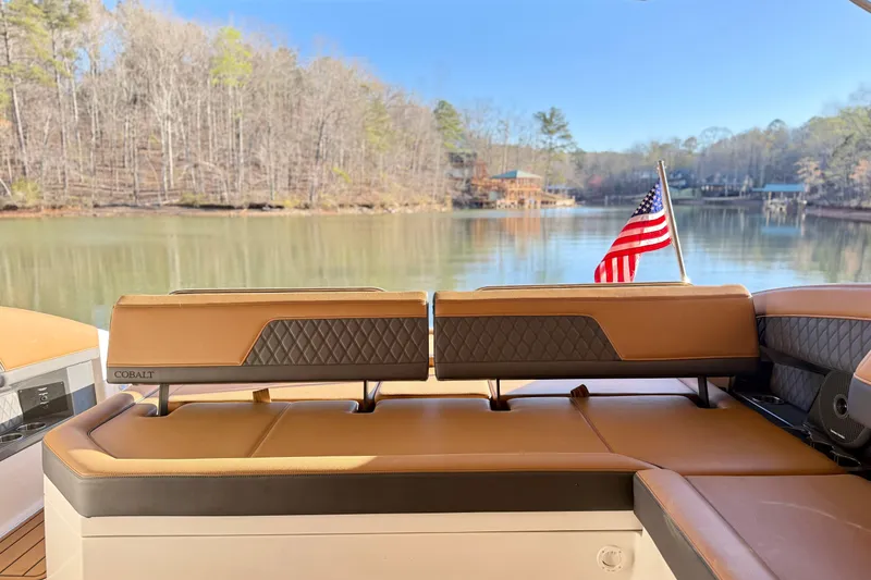 Slide: The Image of 2025 Cobalt R33 boat interior with American flag, overlooking serene lake and wooded shoreline. - 31