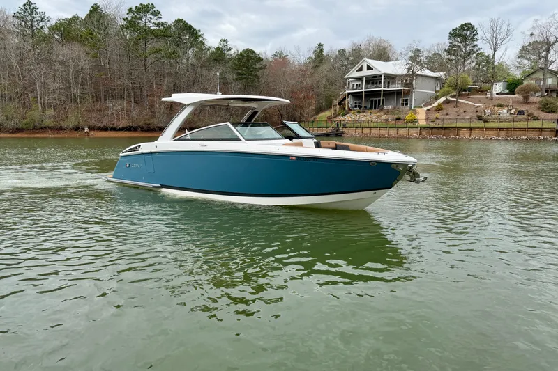 Slide: The Image of 2025 Cobalt R33 boat on a serene lake with houses in the background. - 5