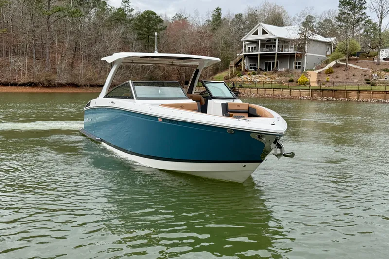 Slide: The Image of 2025 Cobalt R33 boat cruising on a lake near a lakeside house. - 6