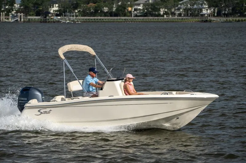 Slide: The Image of 2026 Scout 188 Sportfish boat cruising on a calm lake with two passengers. - 26