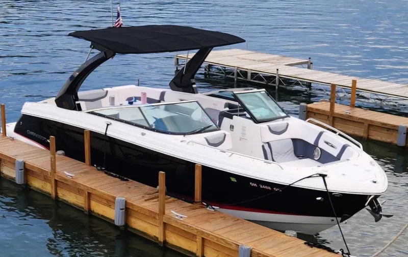Slide: The Image of 2017 Chaparral 287 SSX boat docked on calm water with black canopy. - 4