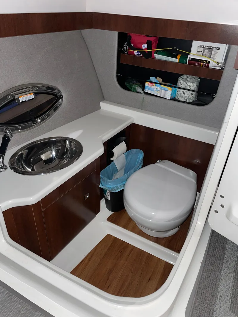 Slide: The Image of 2017 Chaparral 287 SSX boat bathroom with sink, toilet, and storage shelves. - 9