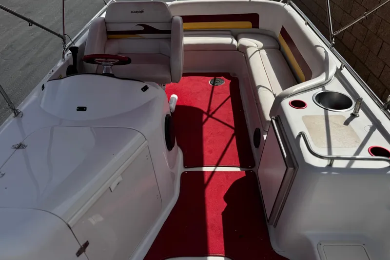 Slide: The Image of Interior of a 2000 Godfrey 248 Fundeck boat with red carpet and seating area. - 16