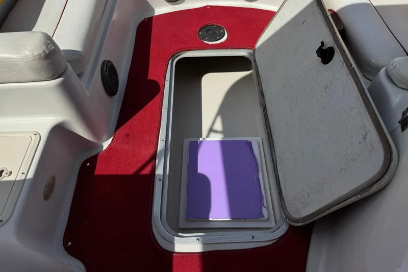 Slide: The Image of Open storage compartment on 2000 Godfrey 248 Fundeck boat with red carpet interior. - 21