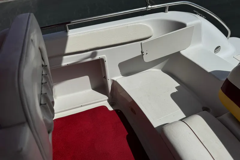 Slide: The Image of Interior of a 2000 Godfrey 248 Fundeck boat with red carpet and white seating. - 24
