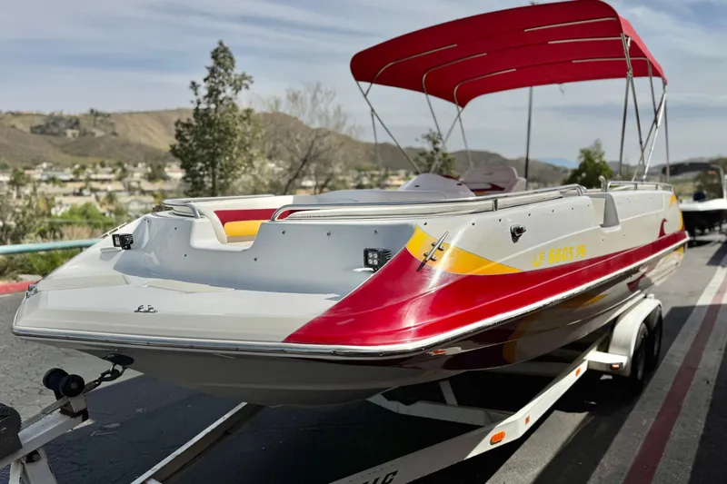 Slide: The Image of 2000 Godfrey 248 Fundeck boat with red and yellow accents on a trailer. - 3