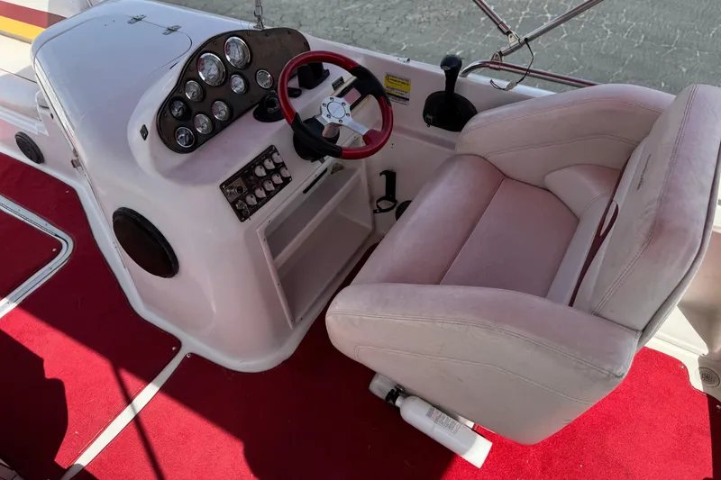 Slide: The Image of Captain's seat and dashboard of a 2000 Godfrey 248 Fundeck boat with red carpet. - 31
