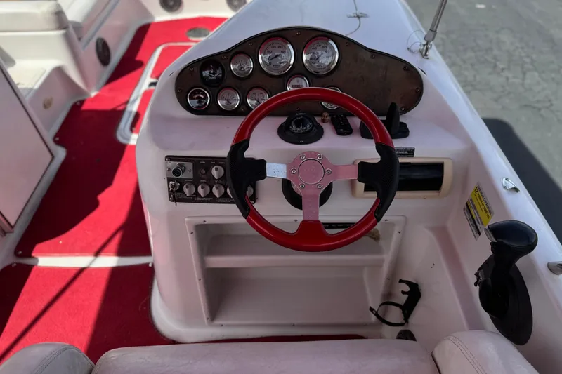 Slide: The Image of Steering console of a 2000 Godfrey 248 Fundeck boat with red accents and gauges. - 32