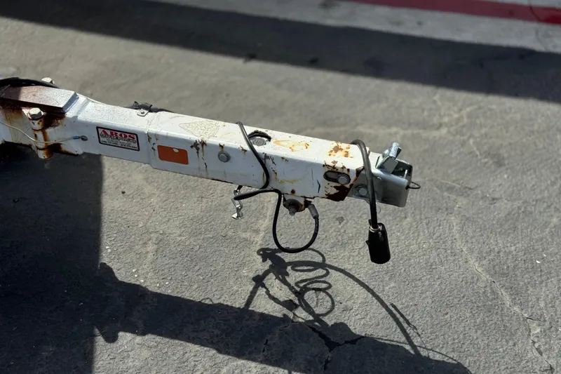 Slide: The Image of Rusty trailer hitch of a 2000 Godfrey 248 Fundeck boat on pavement. - 36