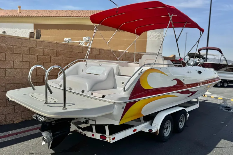 Slide: The Image of 2000 Godfrey 248 Fundeck boat with red canopy and vibrant side graphics on trailer. - 5