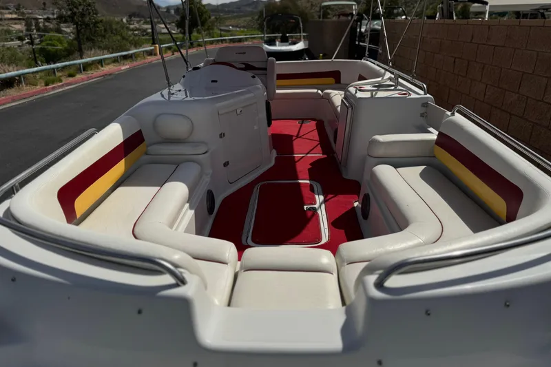 Slide: The Image of 2000 Godfrey 248 Fundeck boat interior with red and yellow seating, docked outdoors. - 9