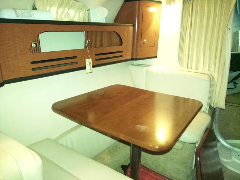 Slide: The Image of Interior of 2005 Sea Ray 280 Sundancer with wooden table and cushioned seating. - 3
