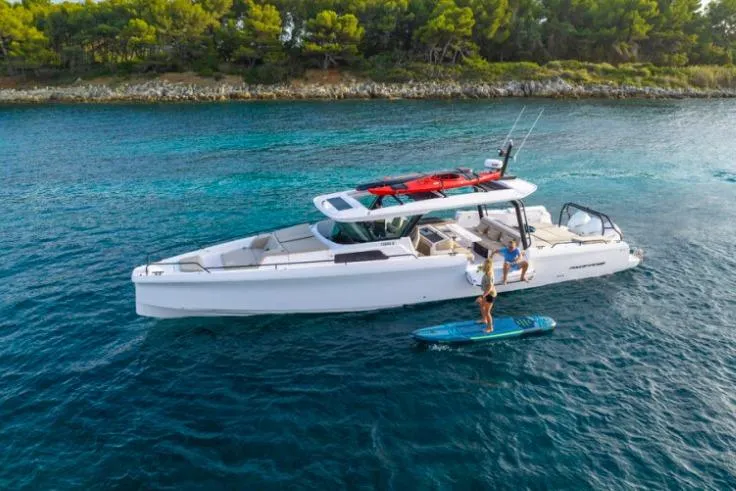 The Image of 2027 Axopar 45 Cross Top boat on blue water with paddleboarder nearby. - 0