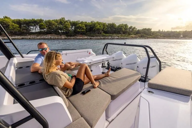 Slide: The Image of Couple relaxing on 2027 Axopar 45 Cross Top boat, enjoying scenic coastal view. - 7