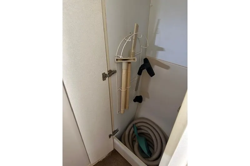 Slide: The Image of Storage compartment in a 1999 Cruisers 3870 Express boat with cleaning tools and hose. - 19