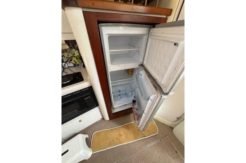 Slide: The Image of Open refrigerator inside 1999 Cruisers 3870 Express yacht, showcasing interior storage space. - 23
