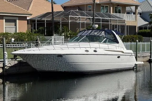 The Image of 1999 Cruisers 3870 Express yacht docked by waterfront homes. - 1