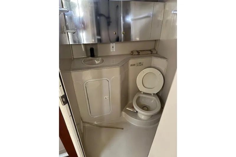 Slide: The Image of 1999 Cruisers 3870 Express boat bathroom with toilet, sink, and storage cabinets. - 17