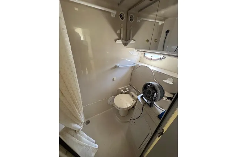 Slide: The Image of Bathroom interior of 1999 Cruisers 3870 Express yacht, featuring toilet and fan. - 22