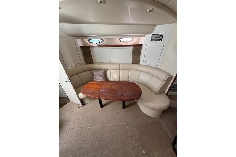 Slide: The Image of 1999 Cruisers 3870 Express yacht interior with curved seating and wooden table. - 24