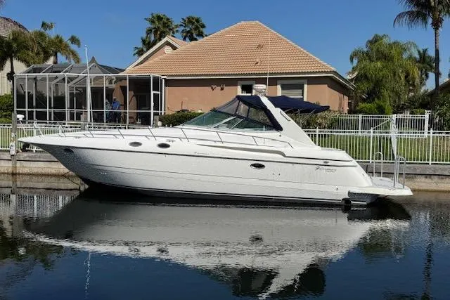 Slide: The Image of 1999 Cruisers 3870 Express yacht docked by a waterfront home. - 3