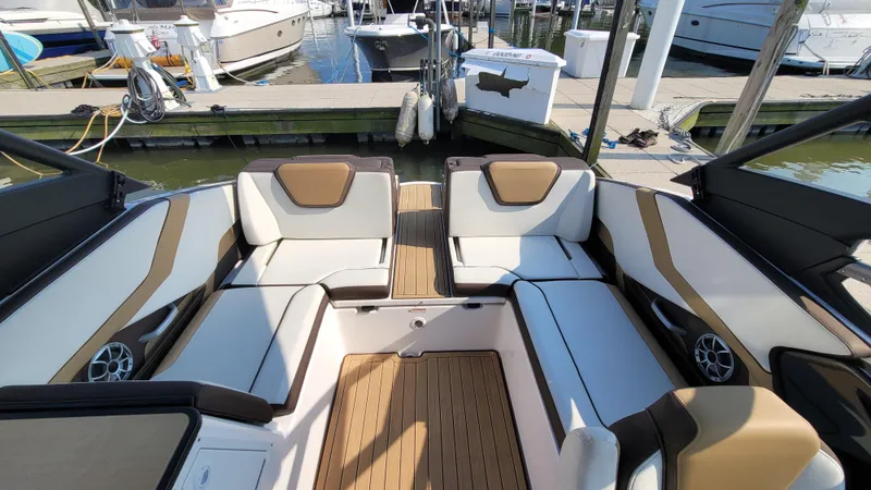 Slide: The Image of 2021 Yamaha Boats 252SD interior with stylish seating and teak flooring at a marina. - 16
