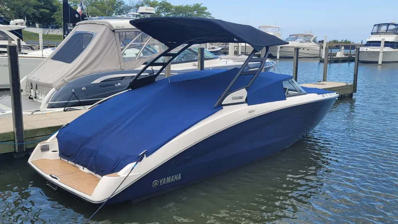 Slide: The Image of 2021 Yamaha Boats 252SD docked, covered with blue canopy and cover, in a marina setting. - 2