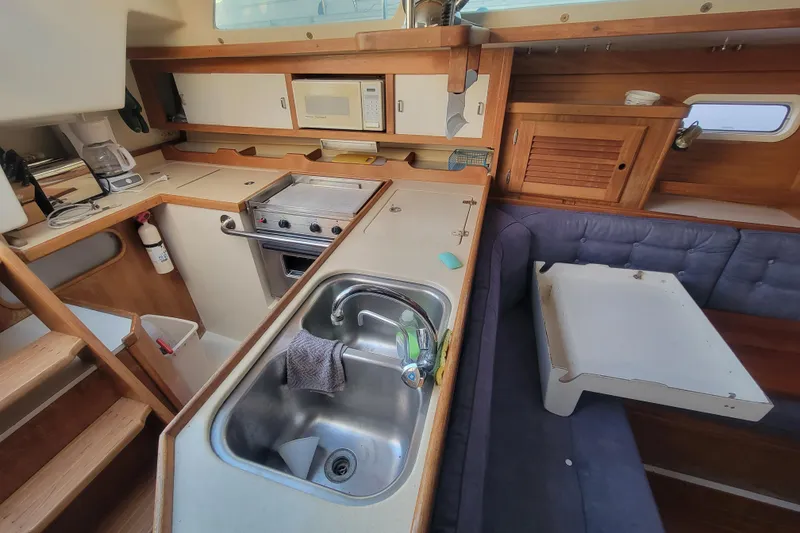 Slide: The Image of Interior of a 1996 Catalina 36 MkII sailboat, featuring a compact kitchen and seating area. - 16