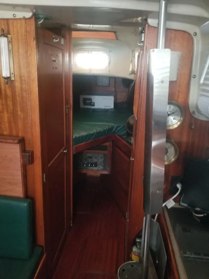 Slide: The Image of Interior of a 1964 Columbia 33 sailboat with wooden cabinetry and green cushions. - 12