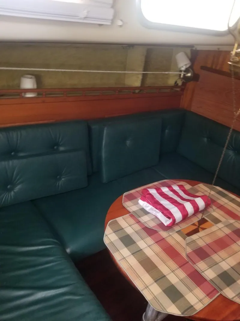 Slide: The Image of Interior of a 1964 Columbia 33 sailboat with green cushioned seating and a wooden table. - 15