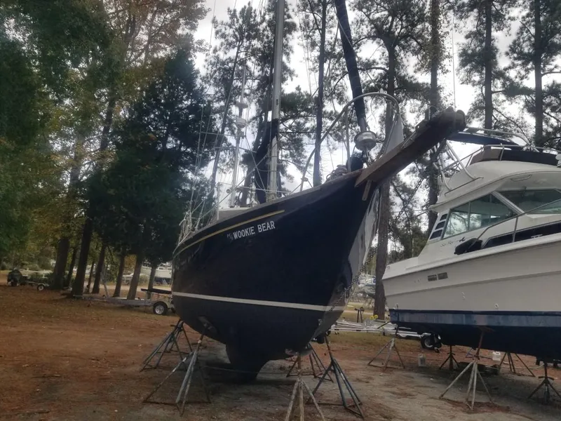 Slide: The Image of 1964 Columbia 33 sailboat named Wookie Bear on dry dock surrounded by trees. - 2
