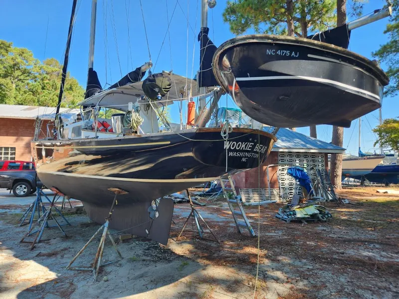 Slide: The Image of 1964 Columbia 33 sailboat Wookie Bear on stands, with a small boat NC 4175 AJ nearby. - 3
