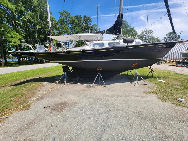 Slide: The Image of 1964 Columbia 33 sailboat on stands in a boatyard, surrounded by trees and other boats. - 4