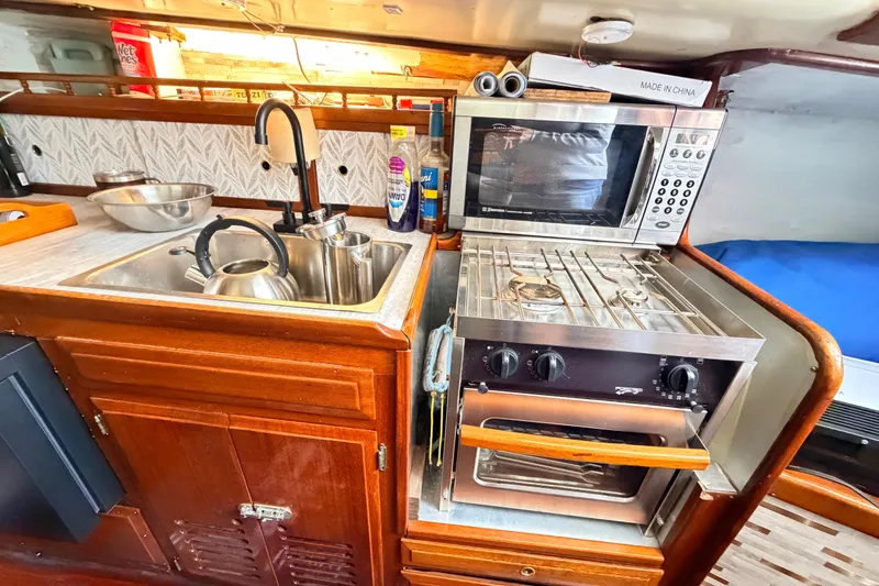Slide: The Image of Compact kitchen in a 1964 Columbia 33 sailboat with sink, stove, and microwave. - 52