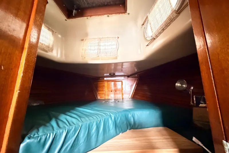 Slide: The Image of Cozy cabin interior of a 1964 Columbia 33 sailboat with wooden accents and teal bedding. - 59