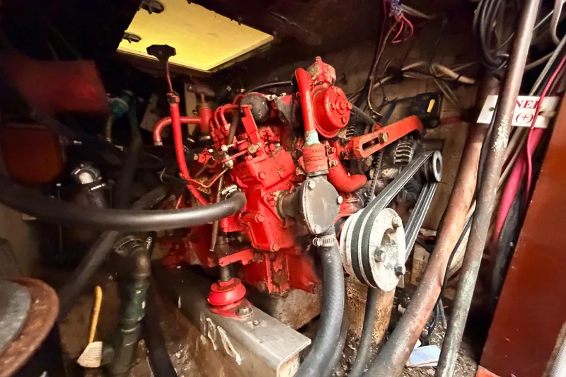 Slide: The Image of Red engine inside a 1964 Columbia 33 boat, surrounded by cables and hoses. - 68