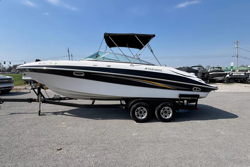 Slide: The Image of 2008 Four Winns H260 RS boat on trailer, parked outdoors under clear sky. - 3