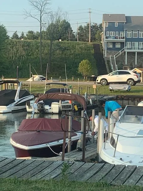 Slide: The Image of 2021 Tahoe 550 TS boat docked at a marina with nearby vehicles and buildings. - 4