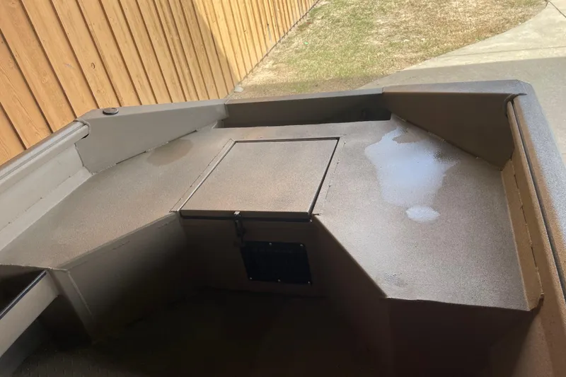 Slide: The Image of 2026 Reaper 653 Timber Reaper boat deck with storage compartment, wet surface, wooden fence background. - 8