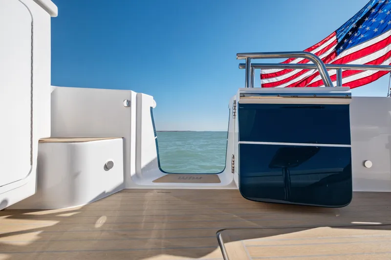 Slide: The Image of MJM 47 R 2026 yacht deck with American flag, ocean view, and clear blue sky. - 38
