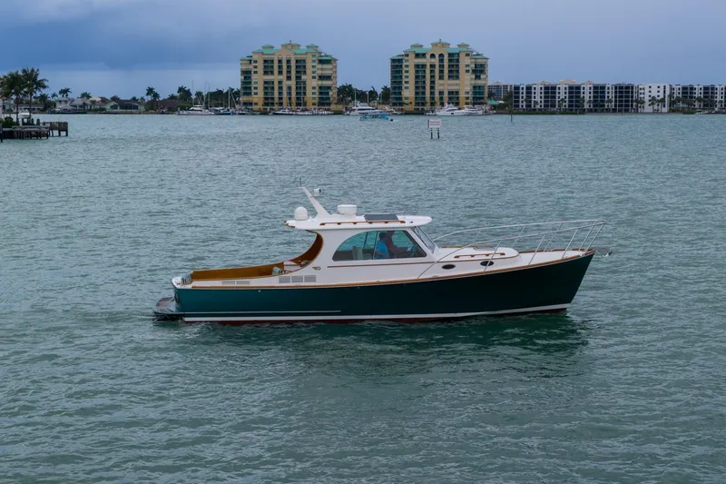 The Image of 2014 Hinckley Picnic Boat 37 MKIII cruising on calm waters near coastal buildings. - 0