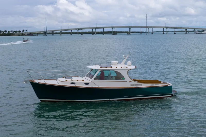 Slide: The Image of 2014 Hinckley Picnic Boat 37 MKIII cruising on calm waters near a bridge. - 1
