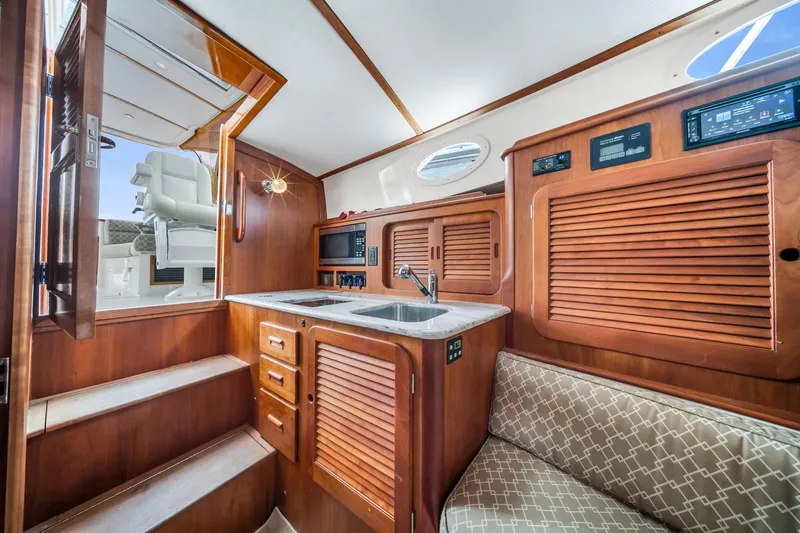 Slide: The Image of Interior of 2013 Hinckley Picnic Boat 37 MKIII with wooden cabinetry and compact kitchen. - 15