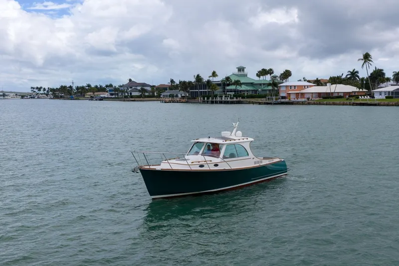 Slide: The Image of 2013 Hinckley Picnic Boat 37 MKIII cruising near waterfront homes under cloudy skies. - 5