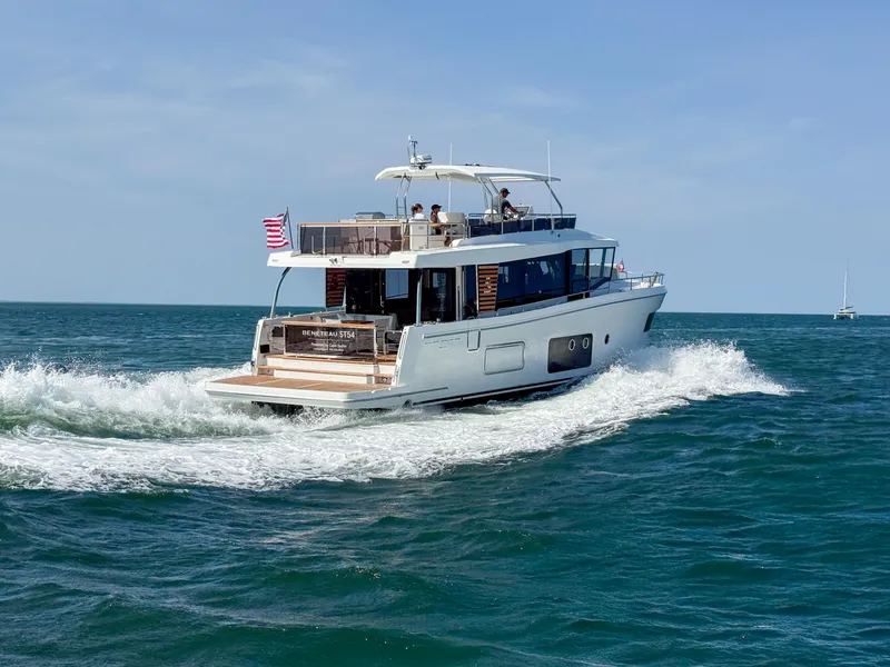 Slide: The Image of 2026 Beneteau Swift Trawler 54 cruising on open sea with American flag. - 2