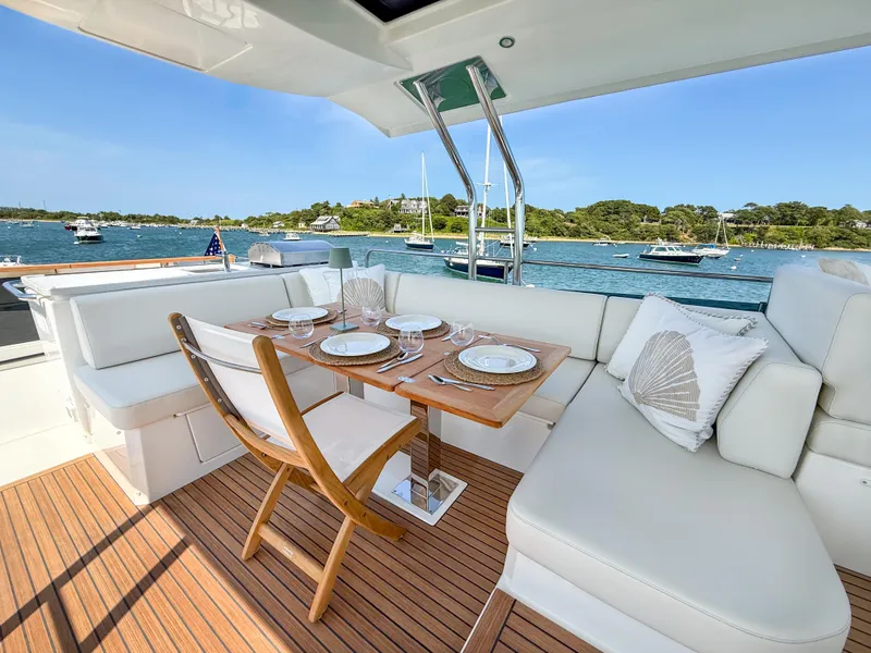 Slide: The Image of Luxurious 2026 Beneteau Swift Trawler 54 deck with elegant dining setup, overlooking serene waters. - 24
