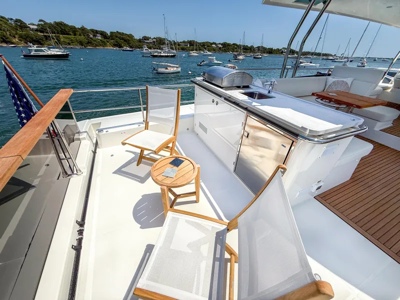 Slide: The Image of Deck of 2026 Beneteau Swift Trawler 54 with seating and outdoor kitchen, overlooking marina. - 25